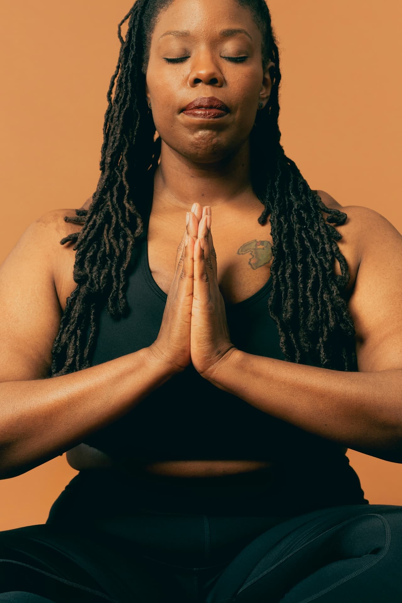 Person in seated meditation with eyes closed and hands in namaste