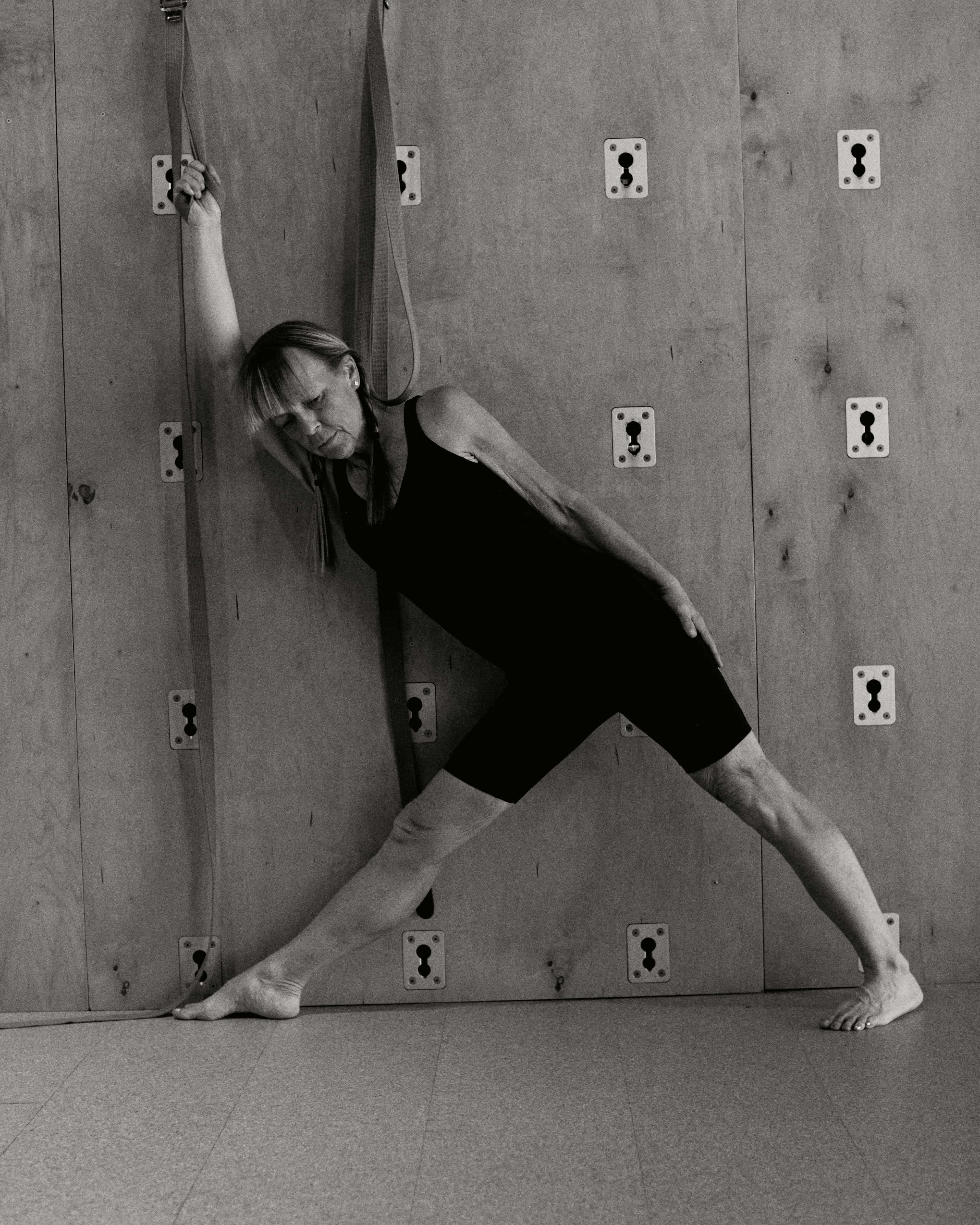 Yoga practitioner in triangle pose against wood wall