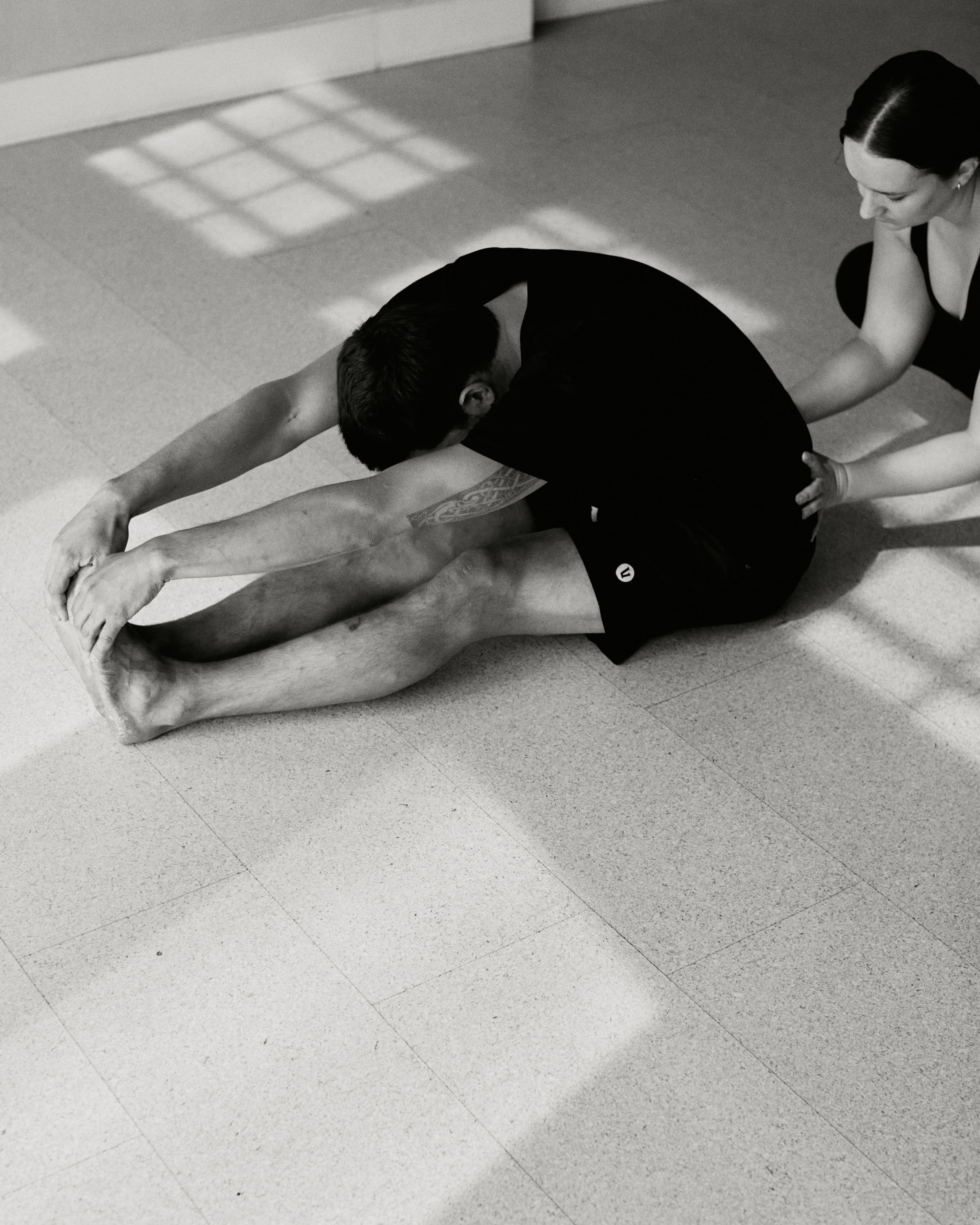 Teacher assisting student in a forward fold