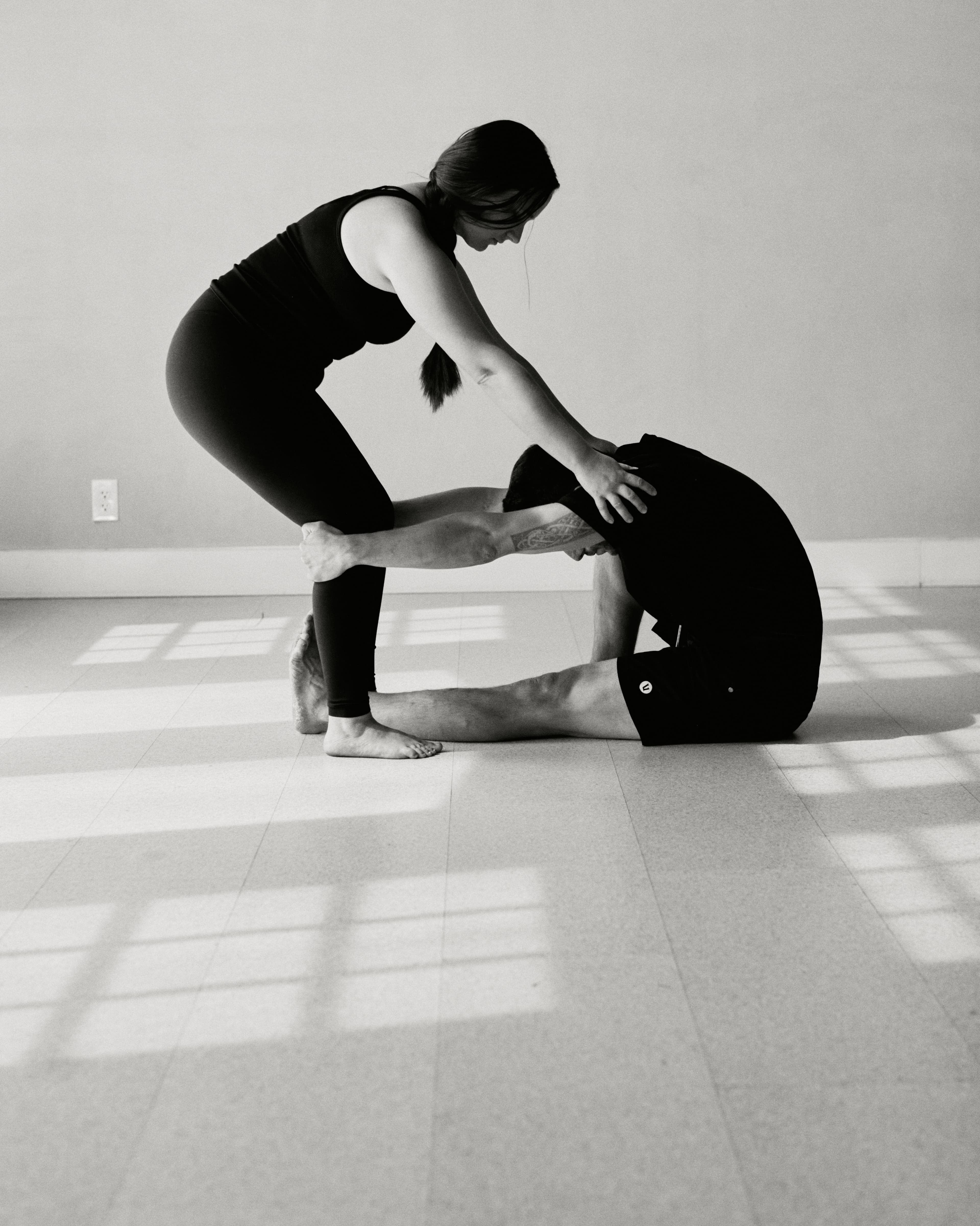 Instructor standing over and assisting student with mat movement