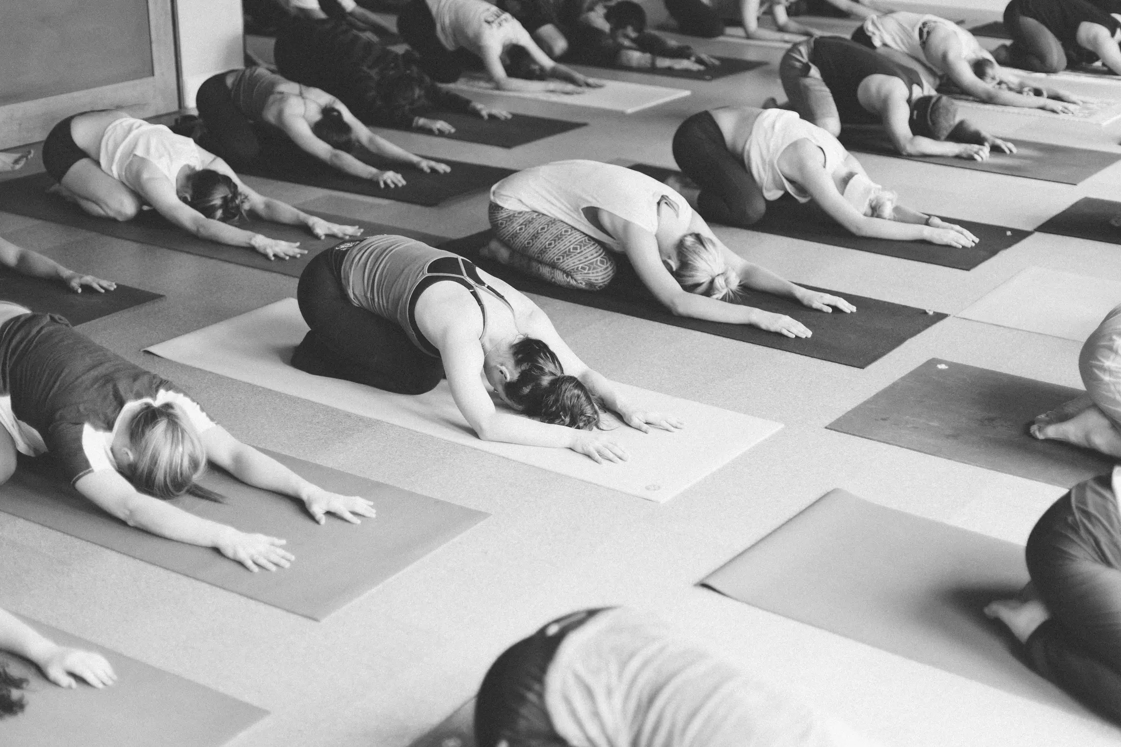 A room of students resting in child’s pose at the end of class
