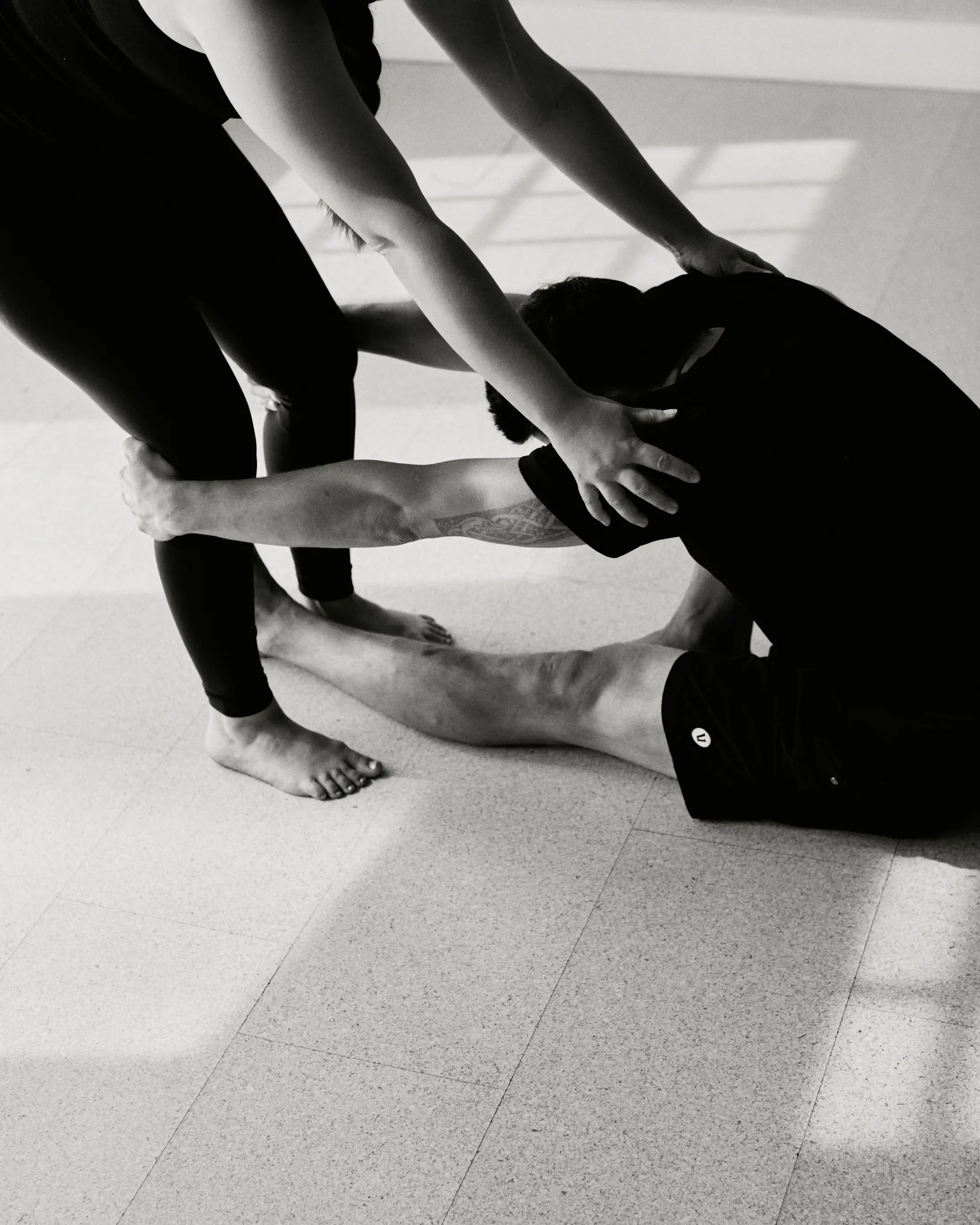 A 3B Movement teacher’s hands guiding a student’s back in a seated forward fold